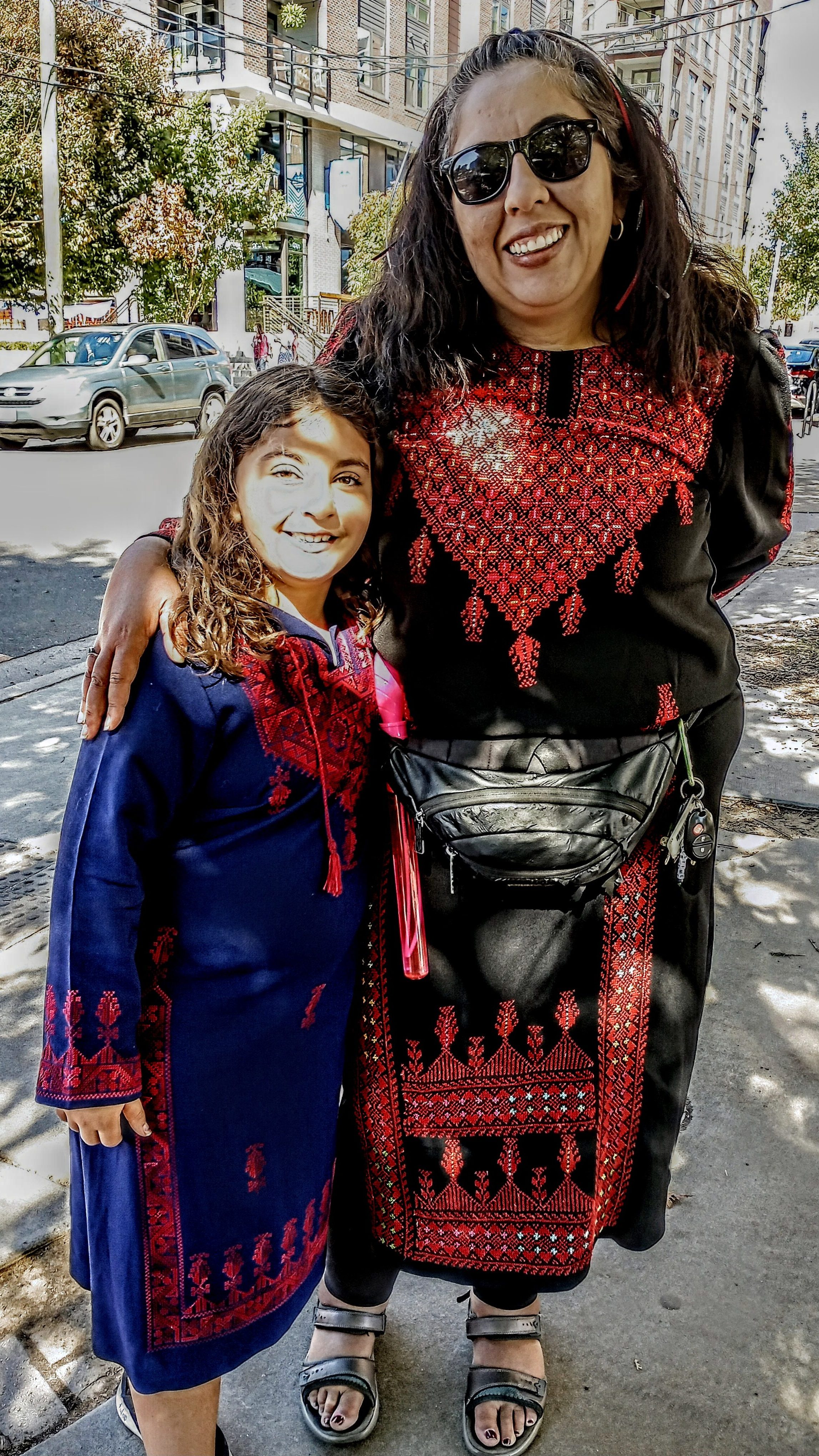 A girl and a woman wearing traditional Palestinian dresses